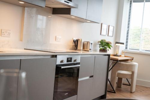 a kitchen with stainless steel appliances and a table at Stylish Spacious Apartment in Central Windsor in Windsor