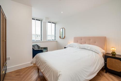a bedroom with a large white bed and two windows at Stylish Spacious Apartment in Central Windsor in Windsor