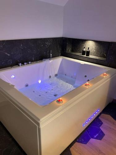 a white bath tub with lights in a room at La Home Love location de séduction in Folles
