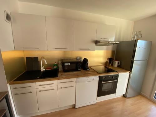 Appartement moderne T3 Cesson في سيسو سُفْيينْ: مطبخ فيه دواليب بيضاء وثلاجة سوداء