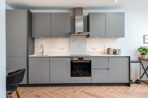 una cocina con armarios blancos y fregadero en Stylish Spacious Apartment in Central Windsor en Windsor