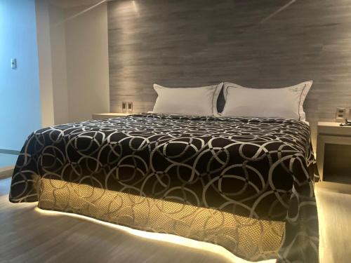 een slaapkamer met een bed met een zwart-wit dekbed bij Hotel Oasis in Mexico-Stad