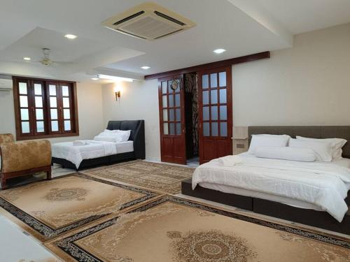 a bedroom with two beds and a couch and a chair at Omar Little Palace - 10 Bedroom Homestay Seremban in Seremban
