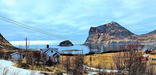 a house in front of a mountain with a body of water at Haukland Panorama in Offersøya