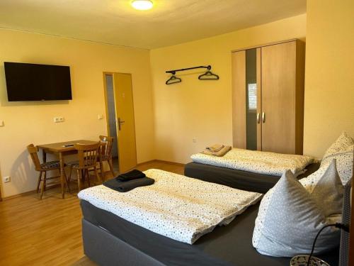 a room with two beds and a table with a television at Ferienwohnung Falkeneck in Lautertal