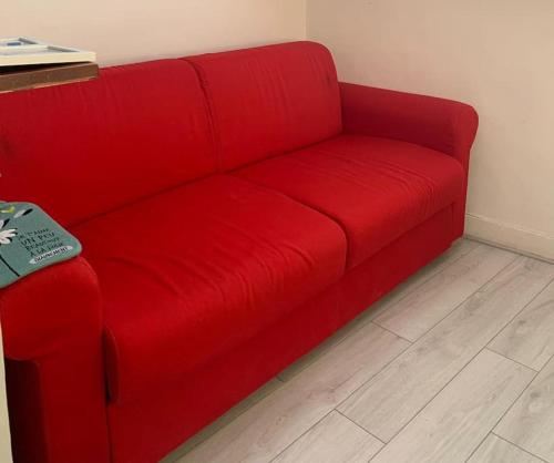 - un canapé rouge dans le salon doté de parquet dans l'établissement Cosy studio Bastille, à Paris