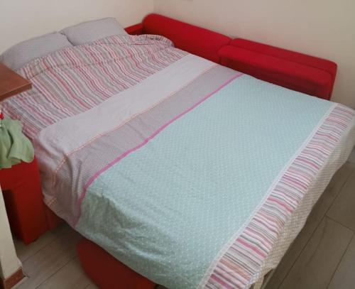 un lit avec un cadre rouge avec une couverture bleue et rose dans l'établissement Cosy studio Bastille, à Paris