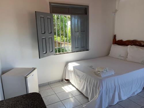 a white bedroom with a bed and a window at Recanto do Porto _ Hospedagem in Cayru