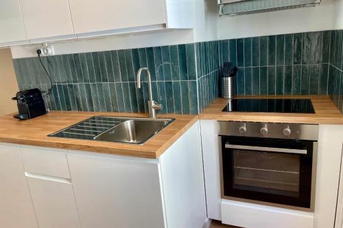 une cuisine avec des armoires blanches, un évier et une cuisinière dans l'établissement Nice appt close to Notre-Dame de la Garde, à Marseille