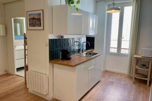 une cuisine avec des armoires blanches et un plancher en bois dans l'établissement Nice appt close to Notre-Dame de la Garde, à Marseille