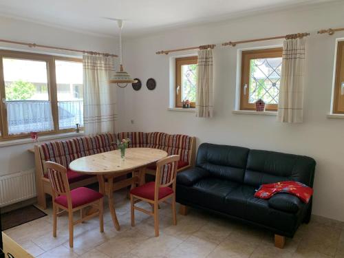 a living room with a table and a black leather couch at Haus Pistenblick in Dienten am Hochkönig