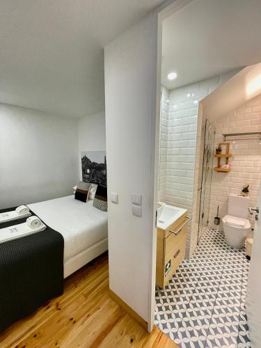 a bedroom with a bed and a bathroom with a sink at 1118 Lofts in Porto