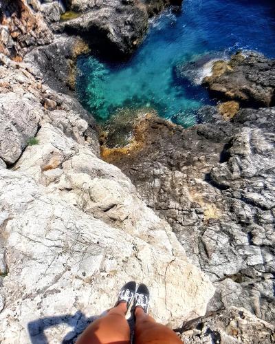a person is sitting on a rock near the water at Charming Villa with Pool, Sea View in Zagora in Zagora