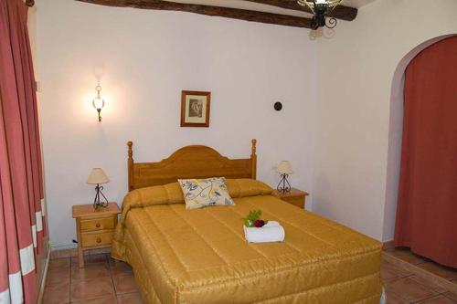 um quarto com uma cama com uma colcha amarela em Cortijo Villarosa em Benablón