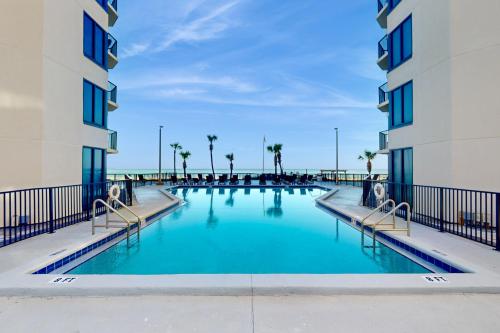 una piscina tra due edifici con palme di Sunbird #1002E a Panama City Beach