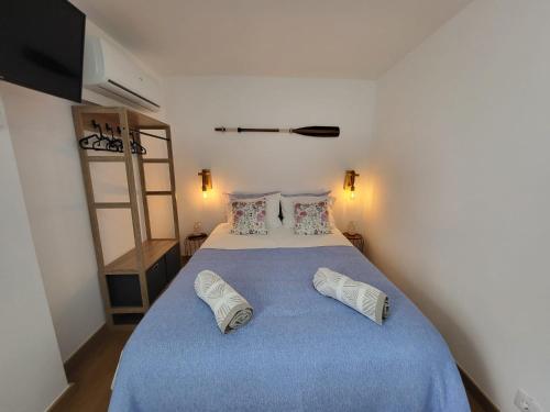a bedroom with a large bed with blue sheets and pillows at Cheirinho a Mar AL in Nazaré
