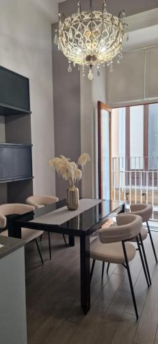 una sala da pranzo con tavolo, sedie e lampadario pendente di Maison Michela Sorrento a Sorrento