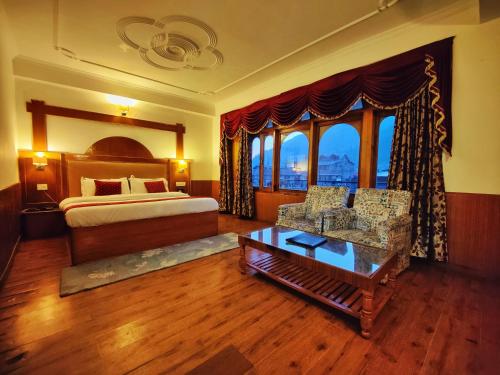 a bedroom with a bed and a couch and a table at Hotel Surya International - Manali in Manāli
