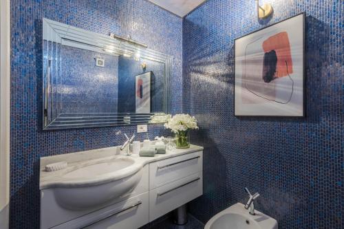 a blue tiled bathroom with a sink and a toilet at De Nobili Penthouse Apartment with Elevator in Lucca in Lucca