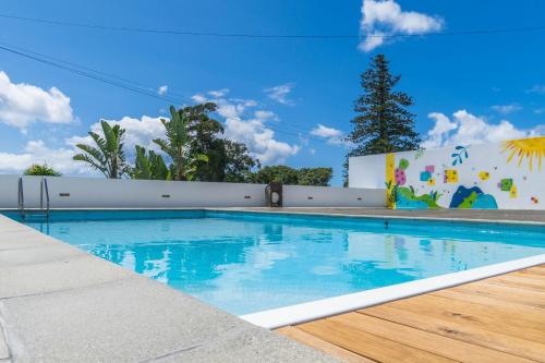 a swimming pool with blue water in front of a building at Azores Dreams - Sea View House in Ponta Delgada