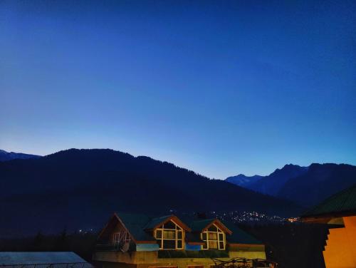 a house with windows and mountains in the background at Surya International Hotel Manali near Mall Road in Manāli