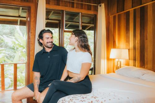 a man and a woman sitting on a bed at Jaguarundi Jungle Lodge - Monteverde in Monteverde Costa Rica