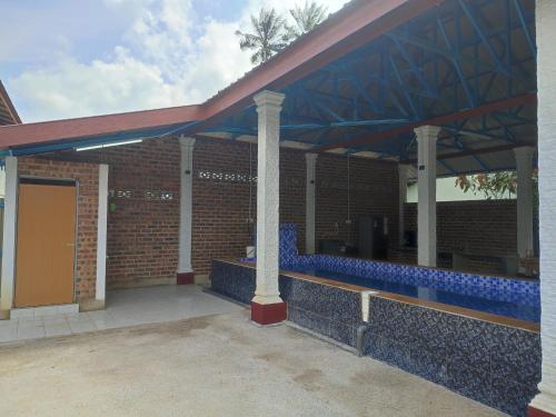 a brick building with a pavilion with blue tiles at Homestay Zamzam in Bachok