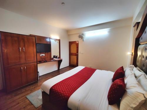 a bedroom with a large bed with red pillows at Surya International Hotel Manali near Mall Road in Manāli