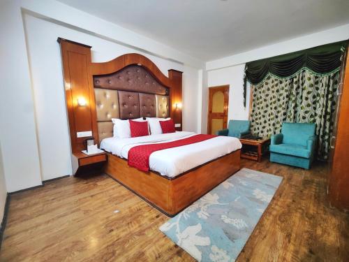 a bedroom with a large bed and two blue chairs at Surya International Hotel Manali near Mall Road in Manāli
