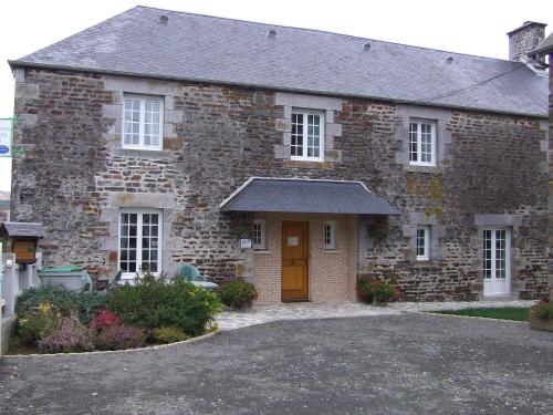 une maison en briques avec une porte orange et une allée. dans l'établissement Les Abris de la Sée, à Tirepied