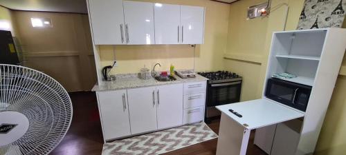 una pequeña cocina con armarios blancos y ventilador en DEBIDIEN APARTMENT, en Paramaribo