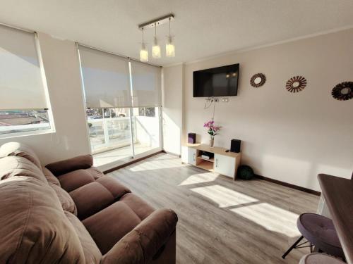 un soggiorno con divano e TV a schermo piatto di Condominio Pacífico III a La Serena