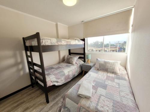 a bedroom with two bunk beds and a window at Condominio Pacífico III in La Serena