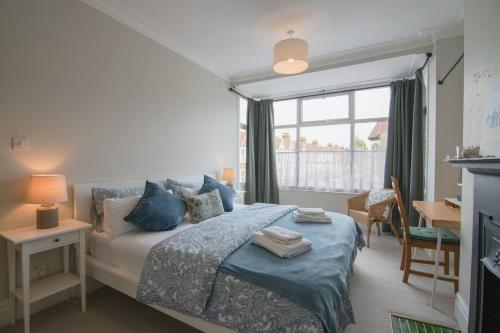 een slaapkamer met een bed met blauwe kussens en een raam bij Pass the Keys Cosy Stylish house near Southend in Southend-on-Sea