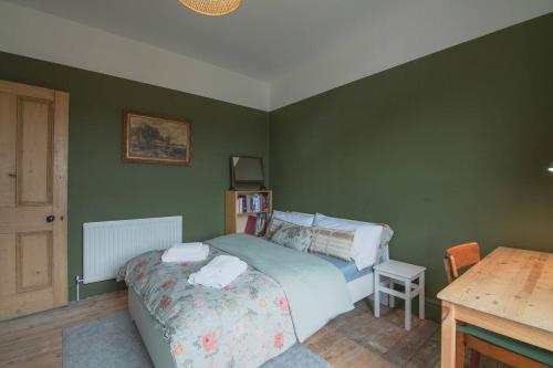 a bedroom with green walls and a bed and a table at Pass the Keys Cosy Stylish house near Southend in Southend-on-Sea