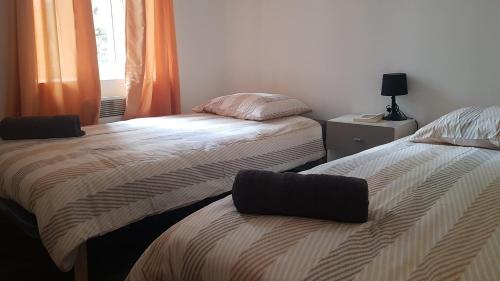1 dormitorio con 2 camas y una ventana con cortinas de color naranja en Appartement en entier, en Saint-Junien