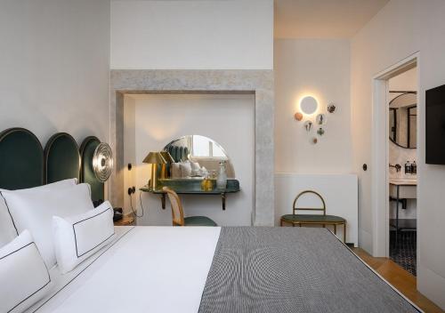 a bedroom with a large white bed and a mirror at Montebelo Vista Alegre Lisboa Chiado Hotel in Lisbon