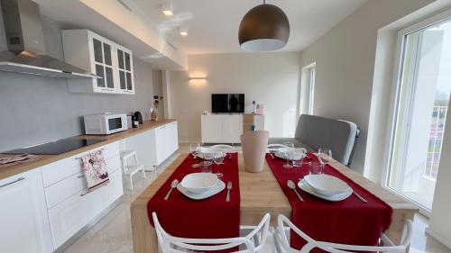 a kitchen and dining room with a red table and chairs at Seafront Modern Flamingo Suite by Ca-Sa Check in Chioggia