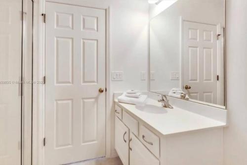 ein weißes Badezimmer mit Waschbecken und Spiegel in der Unterkunft 610 Bungalow at Watersong & pool in Davenport