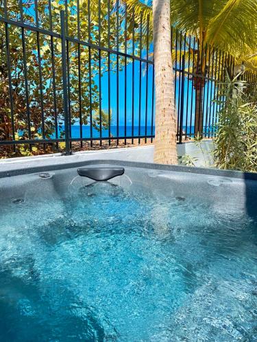 a swimming pool with a palm tree in front of a fence at Kay Alice - Beachfront Villa in Le Carbet