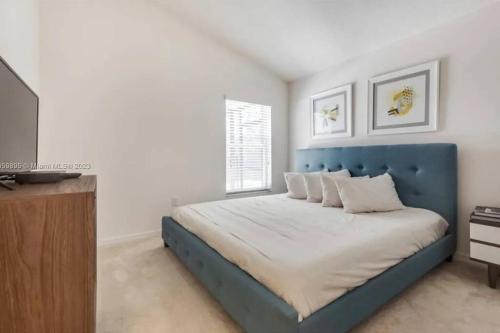 ein Schlafzimmer mit einem Bett mit blauem Kopfteil und einem Fernseher in der Unterkunft 610 Bungalow at Watersong & pool in Davenport