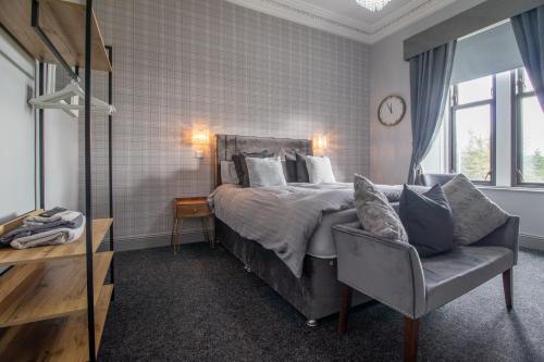 a bedroom with a bed and a chair and a clock at Lugton Rooms in Beith