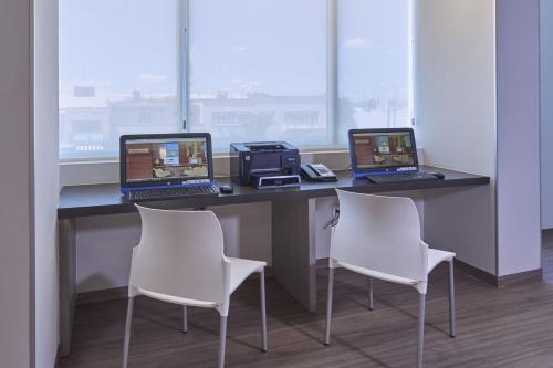 three laptops sitting on a desk with two chairs at City Express Junior by Marriott Ciudad de México Sullivan in Mexico City