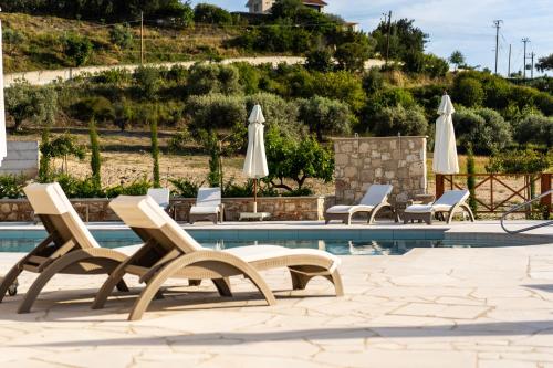 a pool with lounge chairs and umbrellas at Harma Traditional Boutique Suites in Paphos City