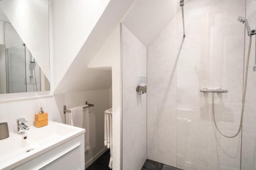 La salle de bains blanche est pourvue d'une douche et d'un lavabo. dans l'établissement La Cour St-Fulrad - Les Suites, à Saint-Hippolyte