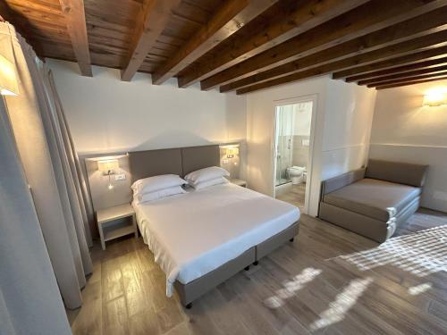 a bedroom with a large white bed and a chair at Hotel Vittoria in Rubano