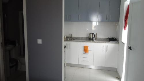 - une cuisine avec des placards blancs et un évier dans l'établissement CasaMrichica1, à Ribeira Grande