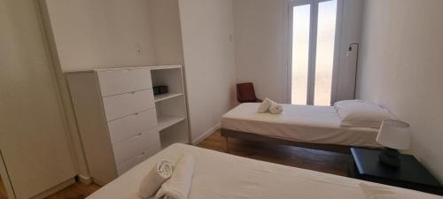 Cette petite chambre blanche comprend 2 lits et une fenêtre. dans l'établissement M.M.R. Gioma, à Cannes