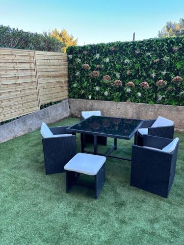 un patio avec une table et des chaises sur l'herbe dans l'établissement Appartement neuf, à Saint-Laurent-du-Var