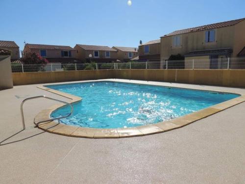 une grande piscine avec de l'eau bleue dans une cour dans l'établissement Fleur De Sel, à Gruissan
